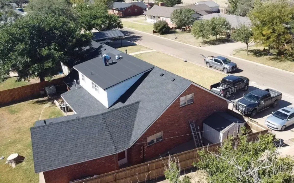 Freshly repaired dark shingle roof on a brick home